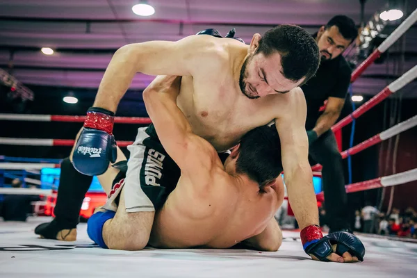 Two fighters mixed martial arts fight on floor of  ring