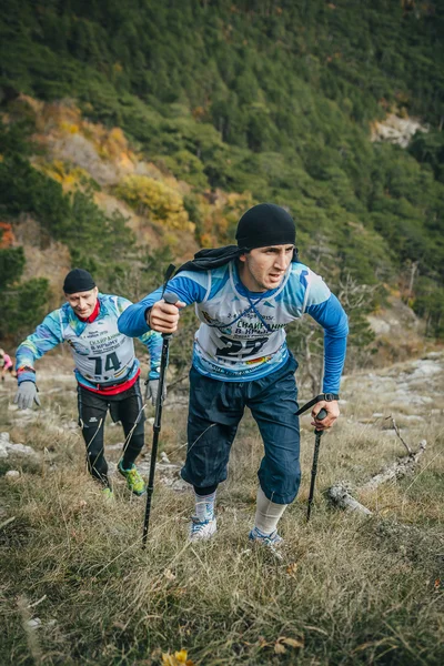 Young athlete marathon runner is ahead of his opponent on a mountain trail