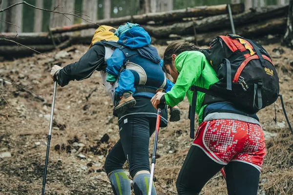 Dad and mom and their child walking on a forest trail in mount