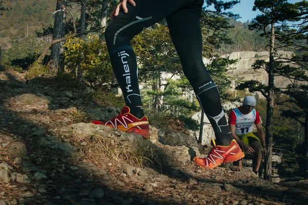 Closeup feet of male runner running uphill on a mountain trail