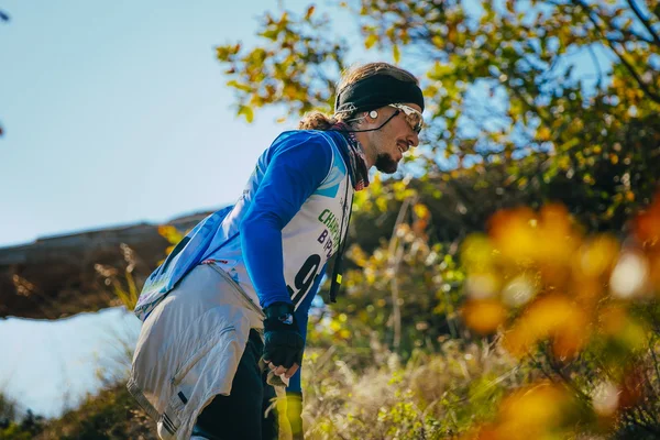 Closeup of young male athlete in headband and glasses. autumn landscape