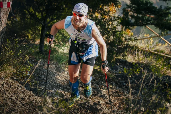 Male athlete in forest is Hiking traill with nordic walking poles