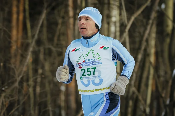 Closeup elderly man runner running on track in winter forest