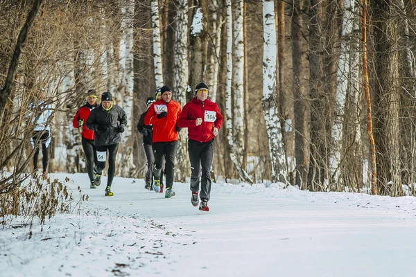 General plan of running on a snowy road in forest group men athletes