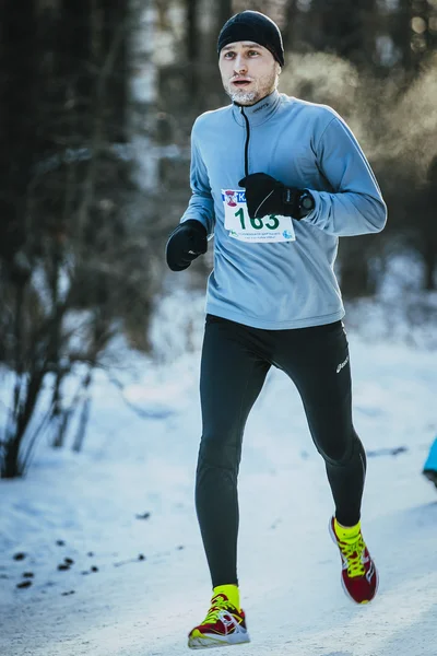 Young male runner running in a winter Park