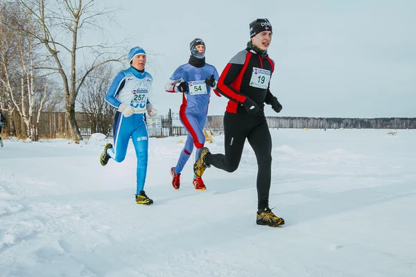 Group of men, leaders race running along shore frozen lake