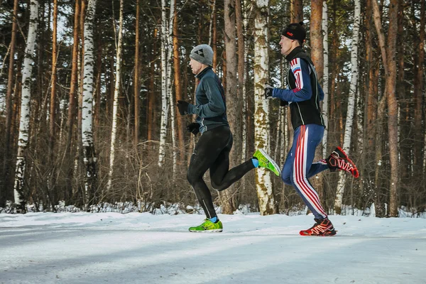 Two men athletes running through woods