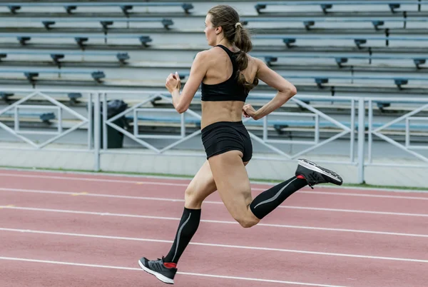 Young woman running at a track and field stadium