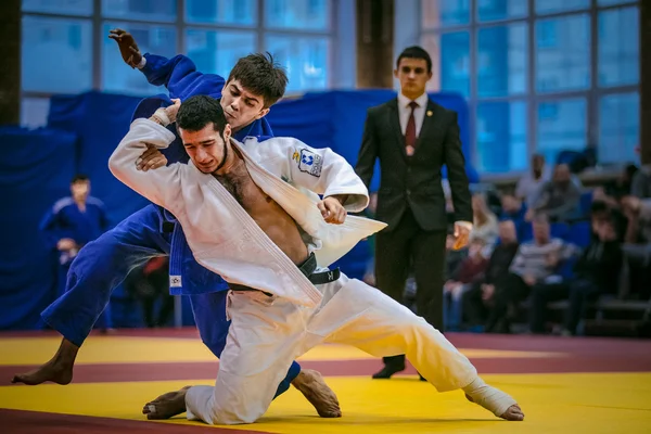 Fight between young male judoists. in background referee