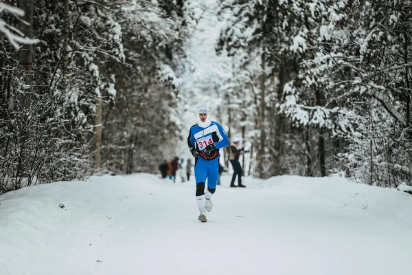 General plan winter forest and young athlete running in cold weather