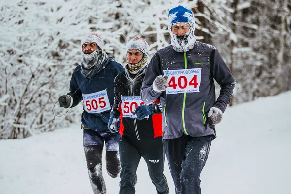 Group men middle age runners running in cold weather in forest