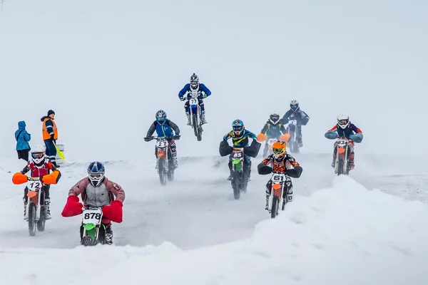 Group young riders on motorcycles are driving snow-covered motocross track