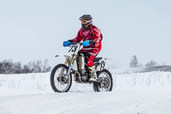 Racer on a motorcycle rides through snowy road race motocross