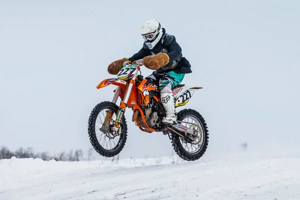 Racer motorcycle rides at speed on a snowy motocross track