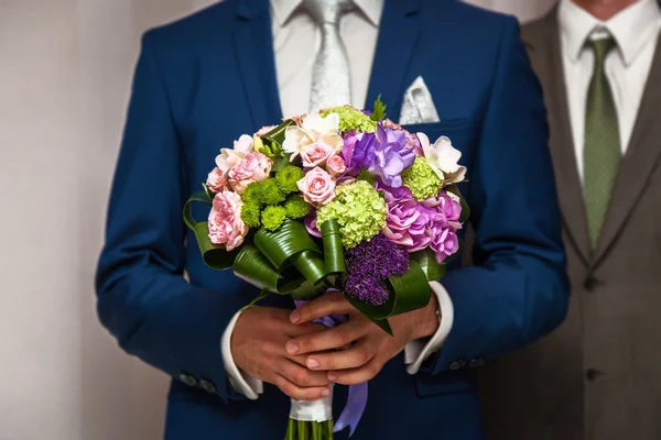 Wedding bouquet in hands of the groom