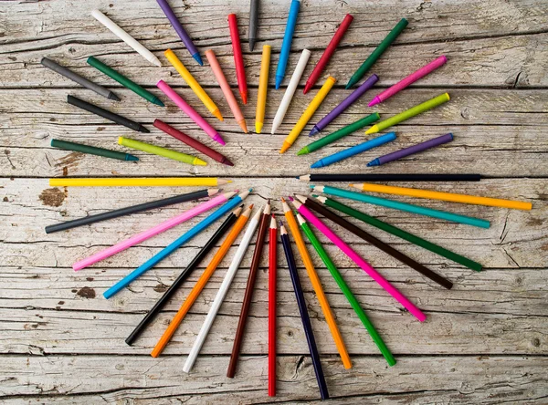 Colorful pencil crayons and wax pencils on wooden background