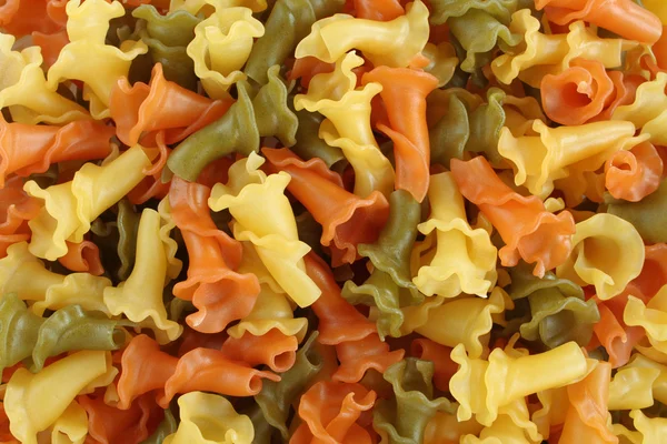 Food background - uncooked three-colored Campanelle durum wheat pasta with spinach and tomato
