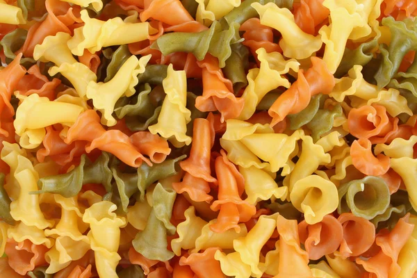 Food background - uncooked three-colored Campanelle durum wheat pasta with spinach and tomato