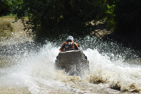 The man on the ATV crosses a stream