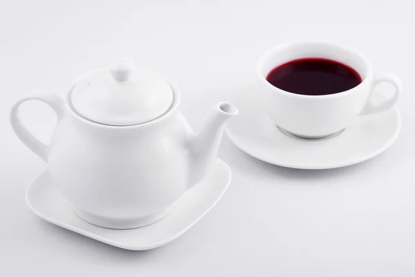 White tea cup with red tea and white teapot on white background
