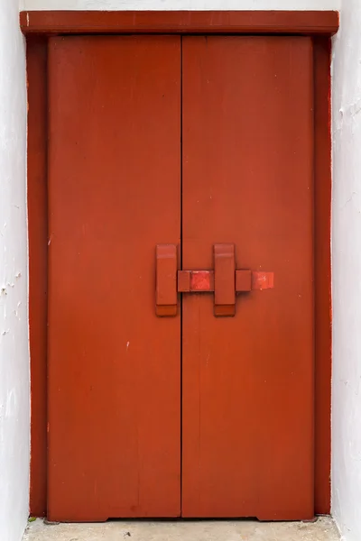 Red wooden door with traditional cross bar lock