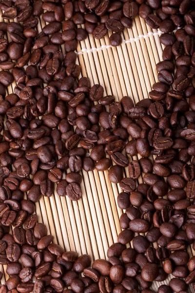 Coffee beans are laid out on a table on a straw or wooden stand.
