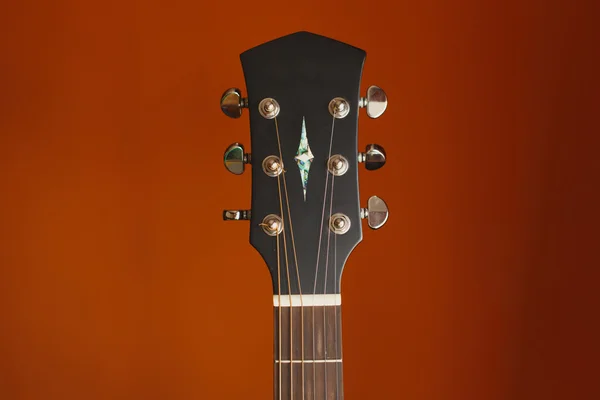 Six-string acoustic guitar on a red background