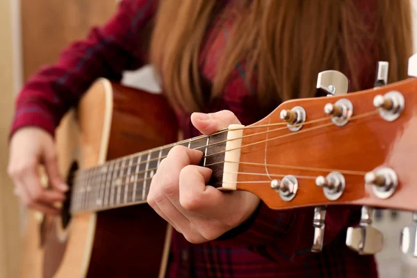 Woman's hands playing acoustic guitar, close up. Playing acoustic guitar girl or woman with long hair by fingers. finger position on the chord. selective focus image