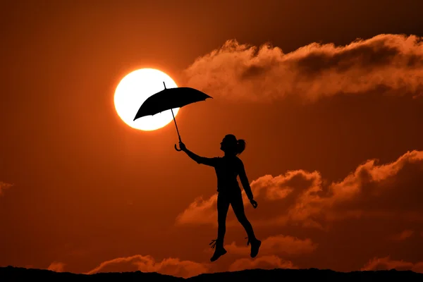 Silhouette of umbrella woman jump and sunset with big sun, landscape