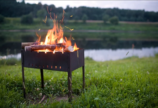 Fire in the grill on the shores of a wild river natural concept