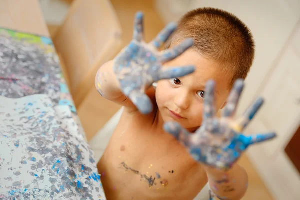 Child shows his hands dirty color while drawing lessons school