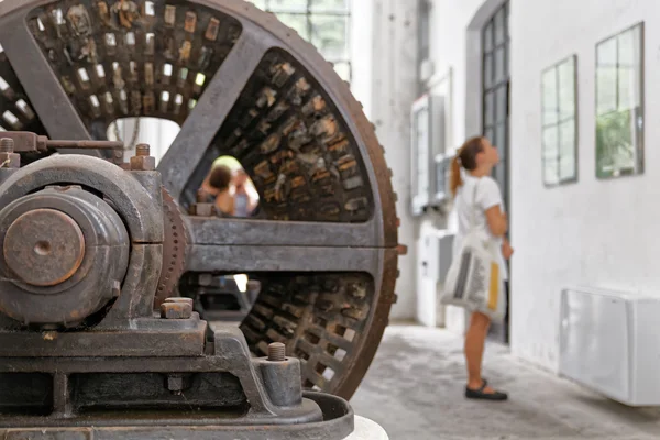 Girl fascinated law documents on the old factory, behind her a huge dryer drum