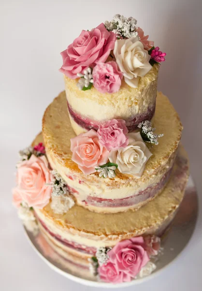 Wedding cake. Naked handmade cake rustic, decorated with roses.