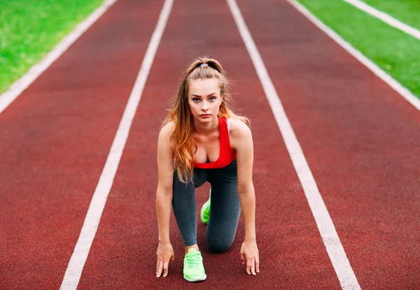 Athletic woman on track starting to run. Healthy fitness concept