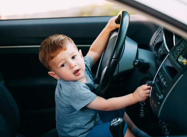 Cute little boy driving fathers car