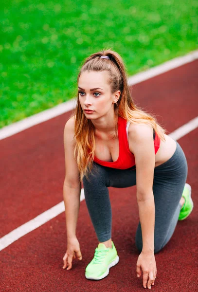 Athletic woman on track starting to run. Healthy fitness concept