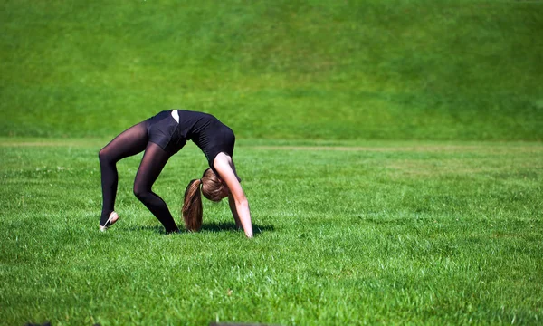 Young gymnast on grass in sunny day