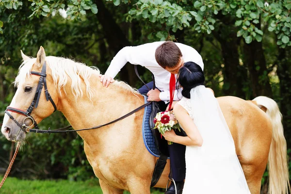 Bride and groom on a horses in the forest