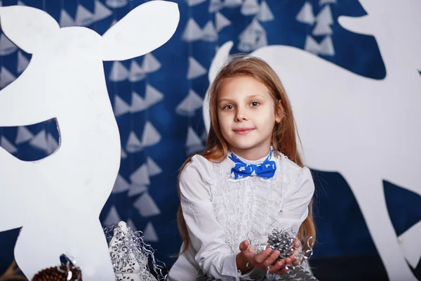 Little girl with bow-tie in christmas decorations.