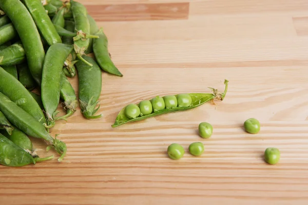 Green peas in pods freshly picked on wood.