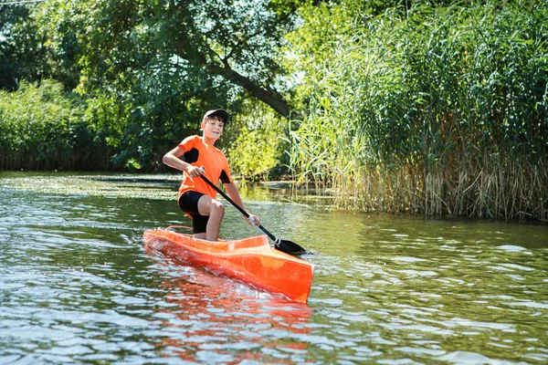 The boy rowing in a canoe on the river.