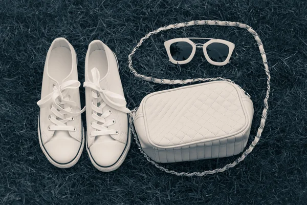 Purse, sneakers and sunglasses with  grass as a background