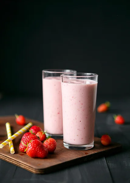 Strawberry and banana smoothie in the glass on black background