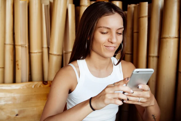 Beautiful girl in a cafe with a phone in his hand. Cheerful girl looking at phone