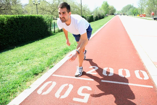 Athletic man on track starting to run