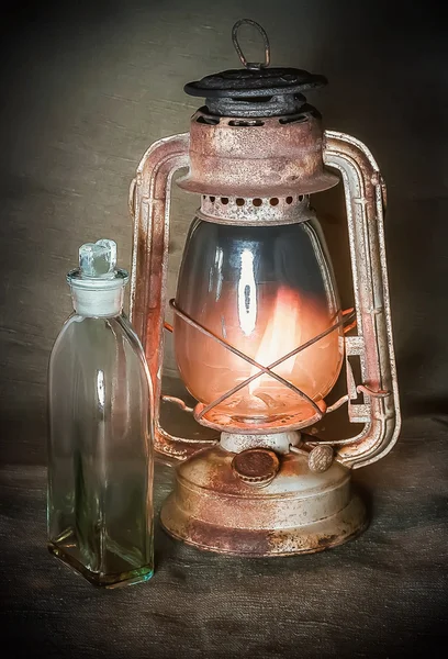 Rusty burning lamp and a bottle of kerosene