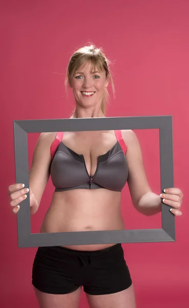 Woman wearing keep fit outfit and holding a picture frame