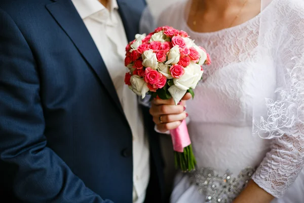 Hands of the bride and groom at a wedding bouquet