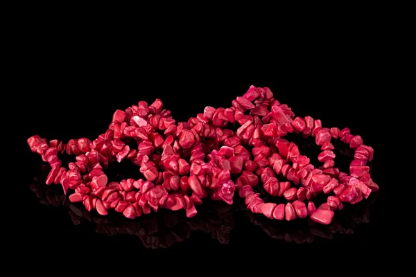 Coral necklace on a black mirror surface