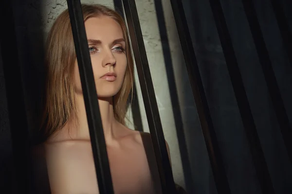 Sad young woman in a cage